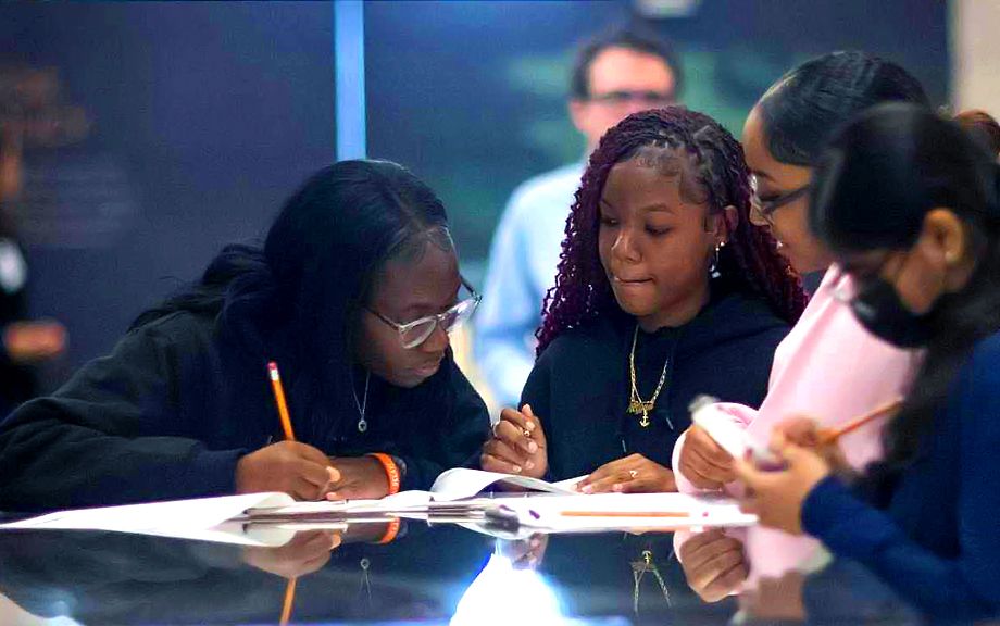 Four students work on an assignment in the New York Fed Museum & Learning Center, as part of the HE3AT program run in partnership with the New York City Department of Education and the Brooklyn South School District.